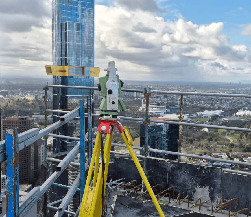 Construction surveying equipment on high rise building site overlooking Melbourne skyline