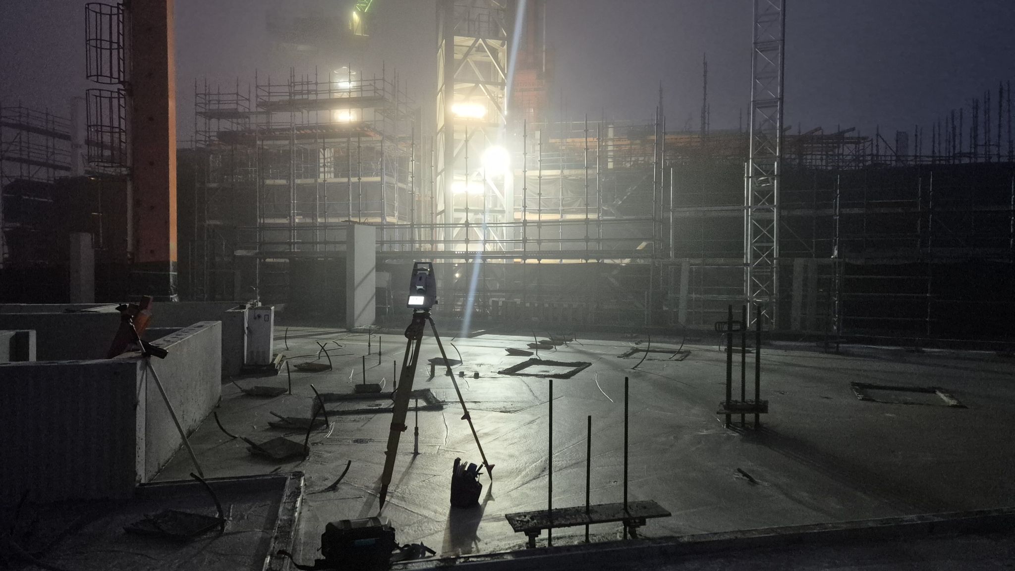 Total station on tripod operating in heavy fog on a Melbourne construction site at night